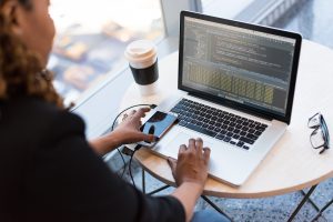Mensch am Tisch vor dem Laptop. Gut geplant ist halb gekauft - gilt auch für den Immobilienkauf als Single. 