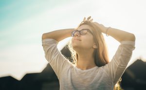 Eine Frau blickt entspannt in die Sonne. Mit der cleveren Baufinanzierung für Alleinlebende gelingt der Immobilienkauf. 