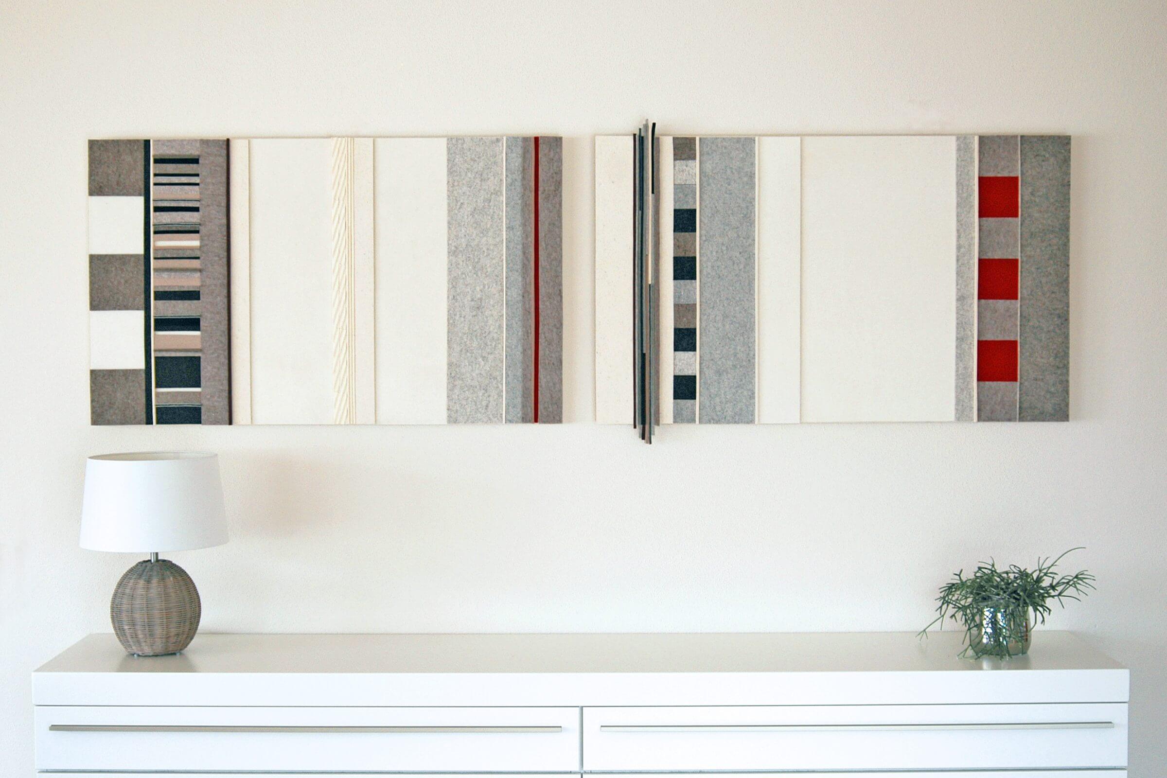 Zwei farbige Akustikbilder hängen über einer weißen Kommode.