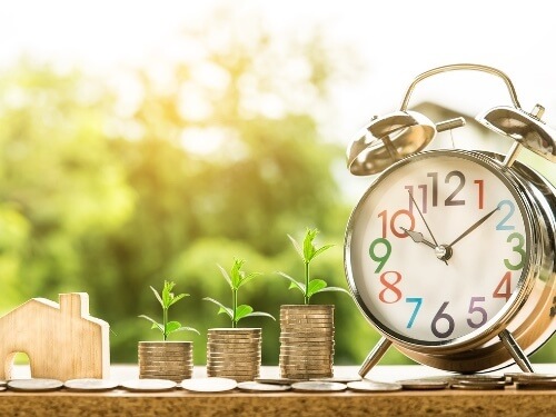 Eine Uhr und Geldmünzen liegen auf einem Tisch.