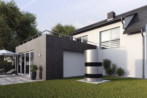 Eine moderne Immobilie in Anthrazit und Weiß mit Terrasse und Garten. Auf dem Rasen steht eine zylindrische Wärmepumpe in silber-anthrazitfarbener Optik, die wie ein Kunstwerk wirkt.