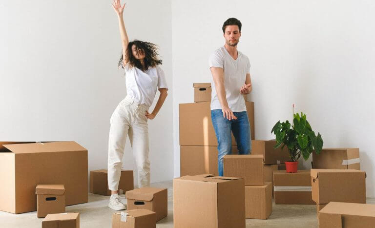 Immobilienkauf 2024 - glückliches Paar neben Umzugkartons