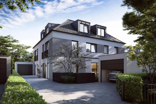 Ein grau-weiß gestaltetes Doppelhaus mit Walmdach und Gauben wird von zwei voneinander separierten Garagen und niedrigen, grünen Hecken flankiert. 