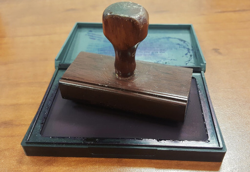 Ein Stempel auf einem Stempelkissen. Zwischen Notartermin und Einzug müssen zahlreiche Formalitäten erledigt werden. 