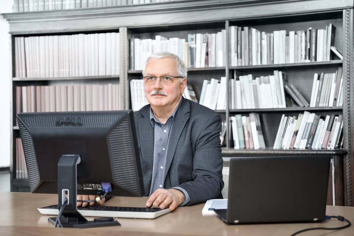 Mann sitzt vor dem Bücherregal