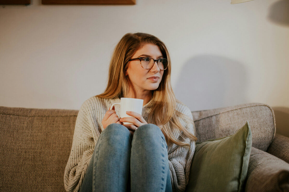 Frau mit Kaffee in der Hand auf dem Sofa