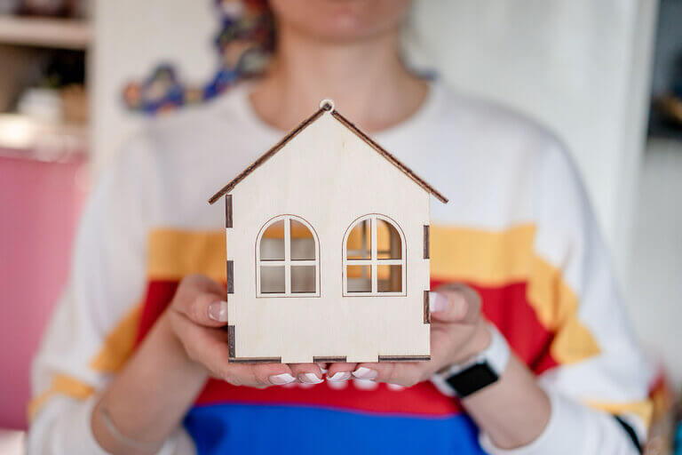 Frau hält Papphaus in Händen