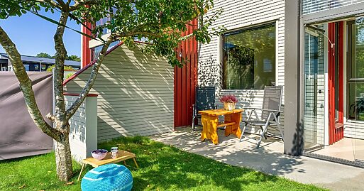 Ein Garten im Erdgeschoss mit zwei Stühlen und einem kleinen Tisch an der Wand unter dem Fenster.